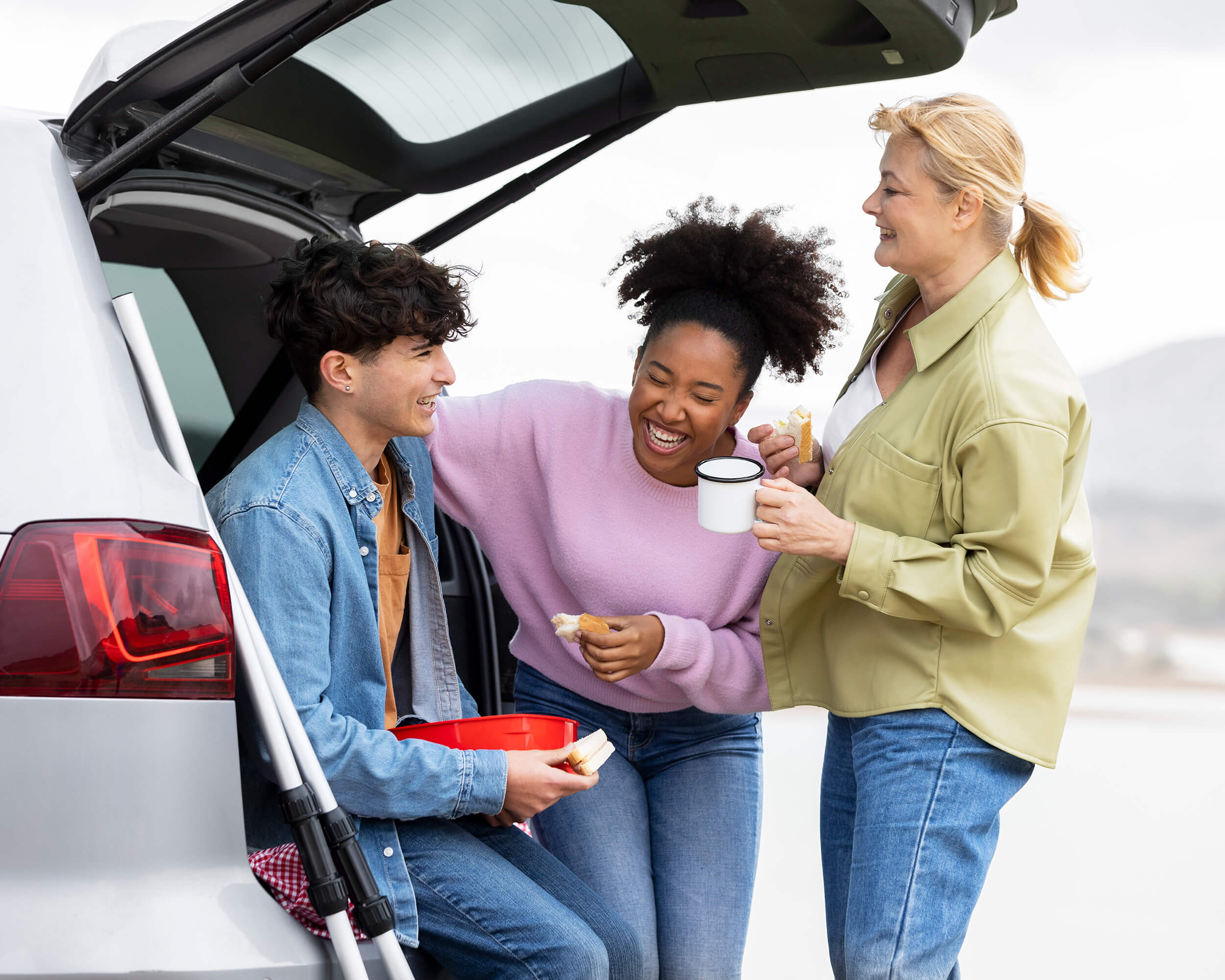Famille qui partage une collation, assise dans le coffre d’une voiture